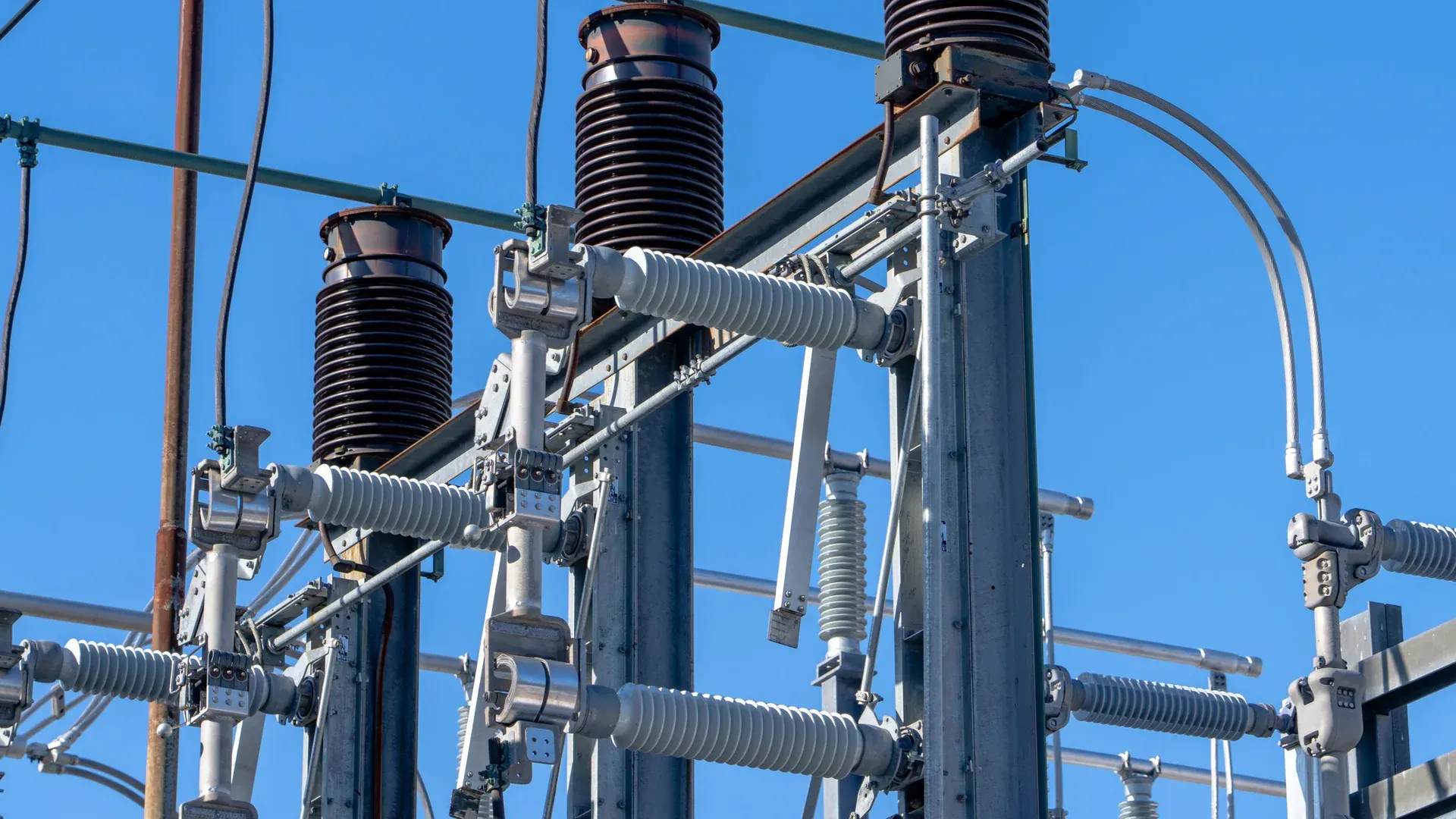 Detailed view of electrical components in a power substation under a clear blue sky