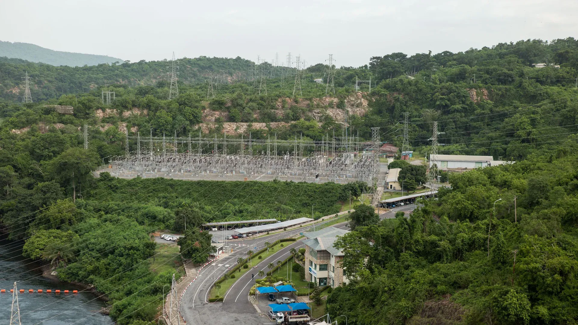 Aerial photograph showcasing a power station surrounded by lush green forest and river