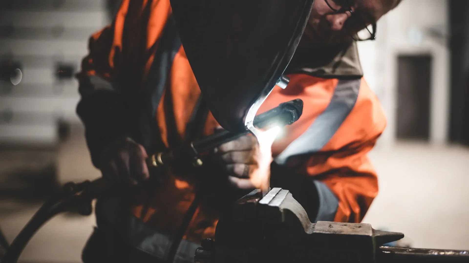 Close-up of a welder wearing safety gear working on metal equipment in an industrial setting
