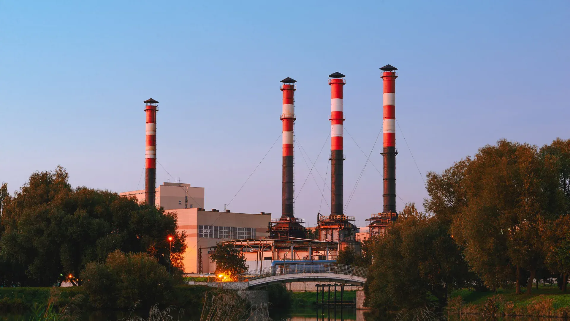 View of an industrial plant with tall chimneys by a lake in Minsk, Belarus during the day