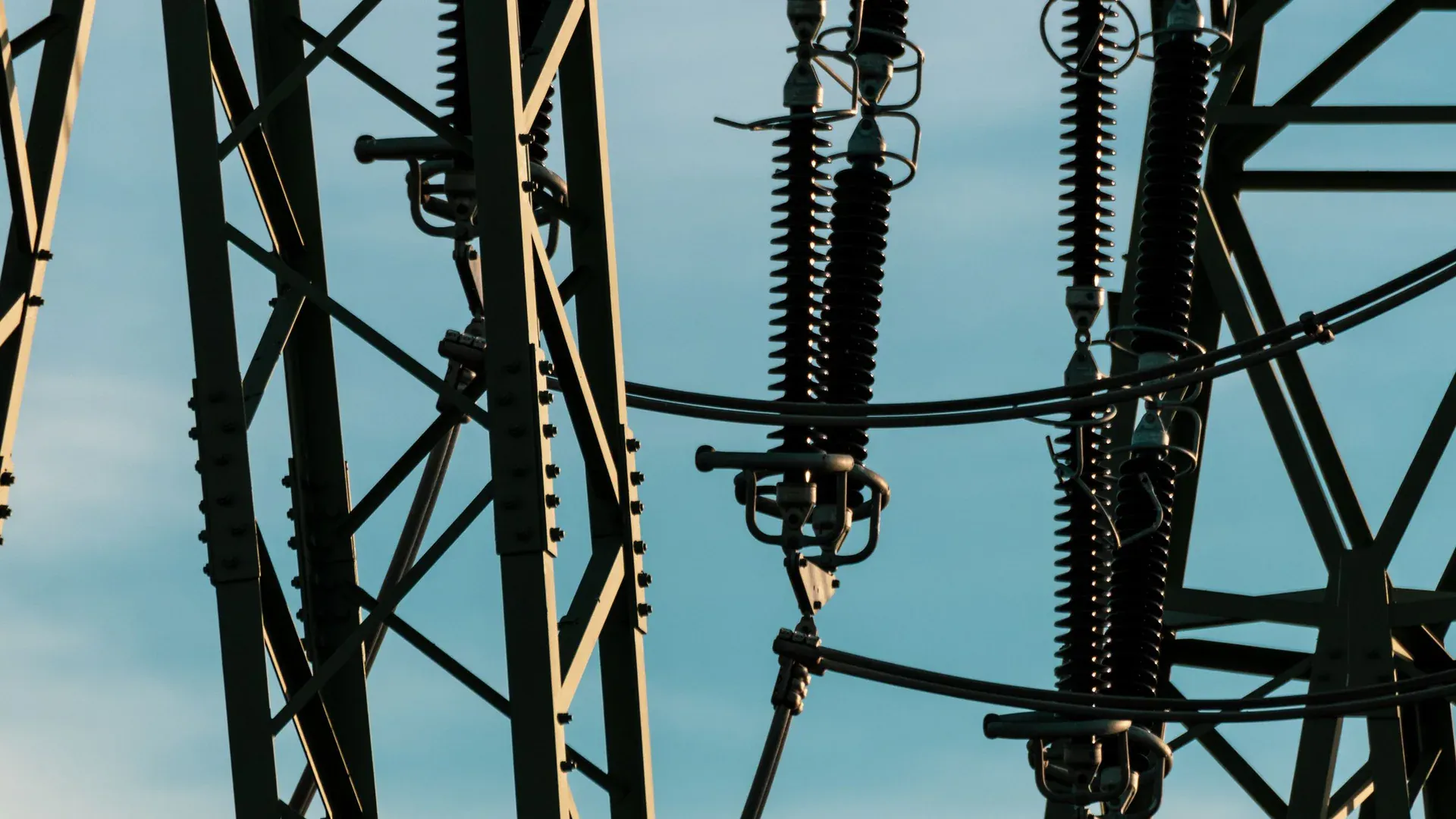 Detailed shot of power lines and electrical insulators set against a vivid blue sky