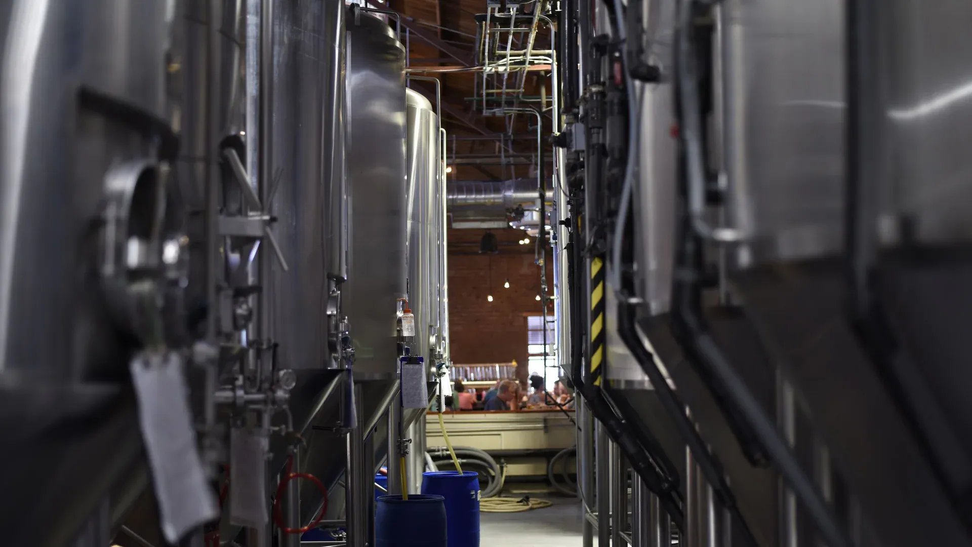 Inside view of a modern brewery with large stainless steel tanks and machinery for beer production