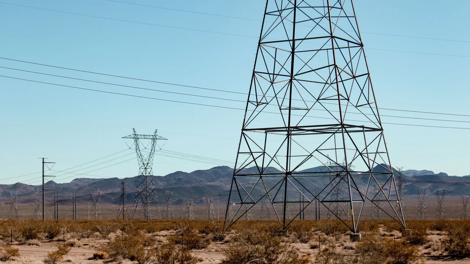 High voltage power lines stand tall in the vast Nevada desert under a clear blue sky