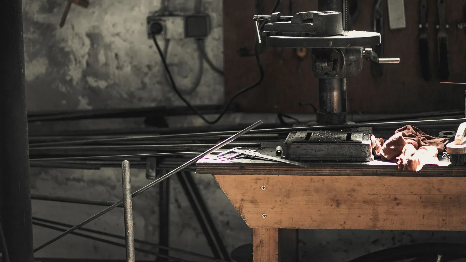 A detailed view of a metalwork workshop showcasing tools, machinery, and steel bars