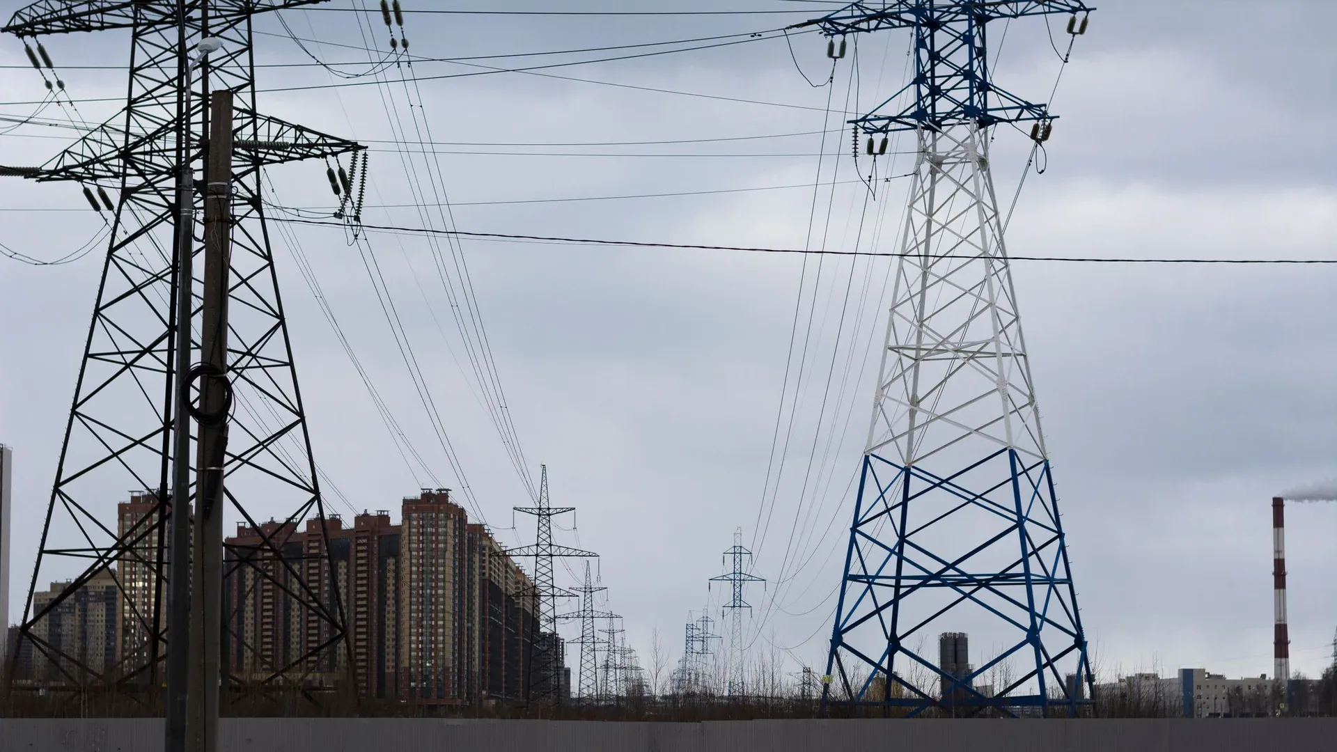 Cityscape featuring electricity pylons against a cloudy sky