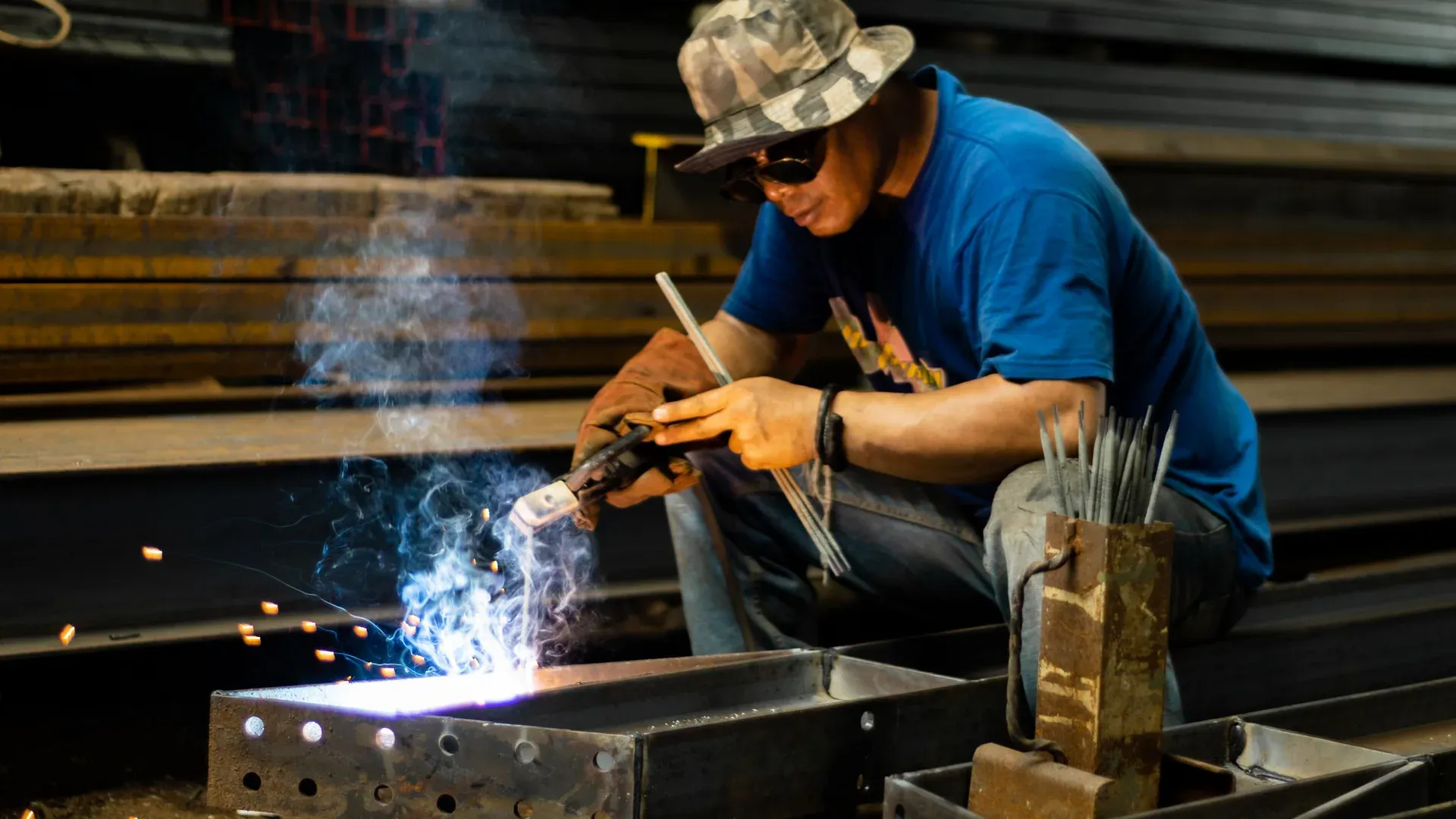A skilled welder wearing protective gear operates in an industrial setting, highlighting craftsmanship and safety