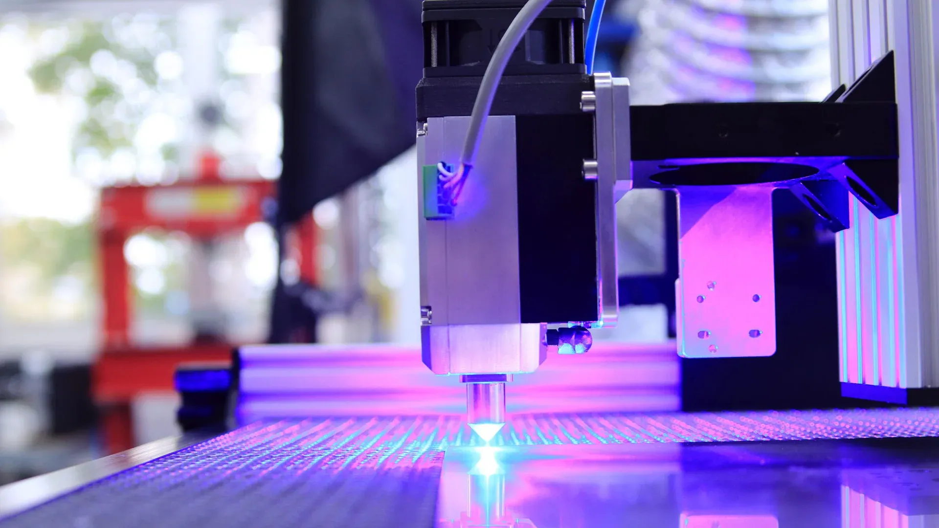 Close-up of a laser engraving machine working indoors with blue light reflection