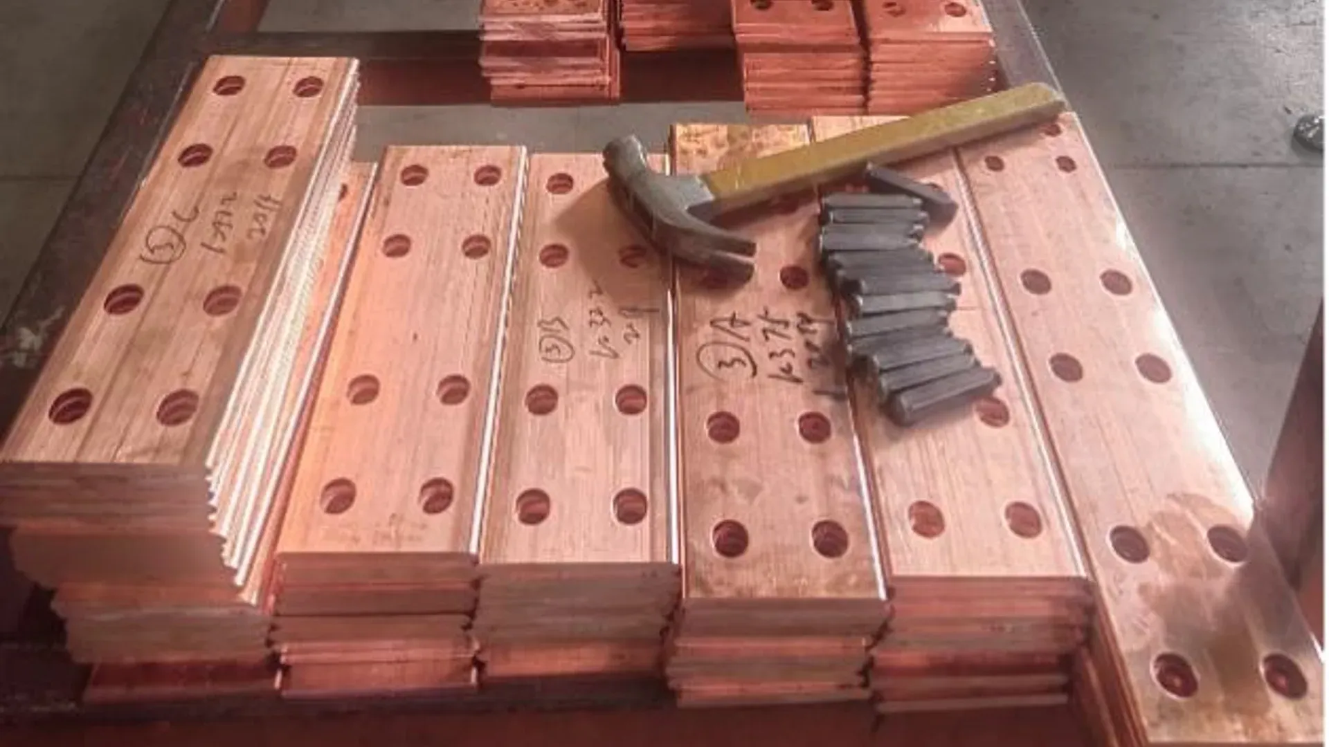 Punched copper busbar parts stacked for material and dimensional inspection