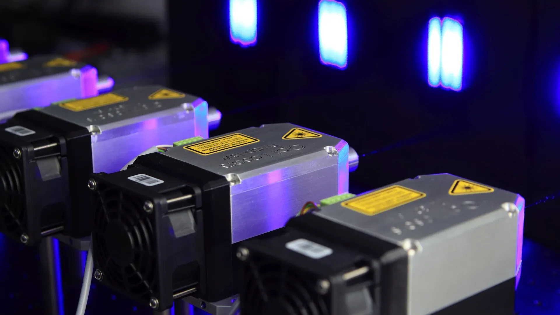 Row of industrial laser modules operating under blue and violet light