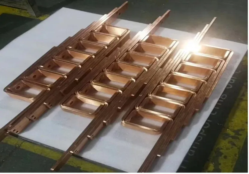 Copper busbar parts with formed offsets and mounting holes arranged on a worktable