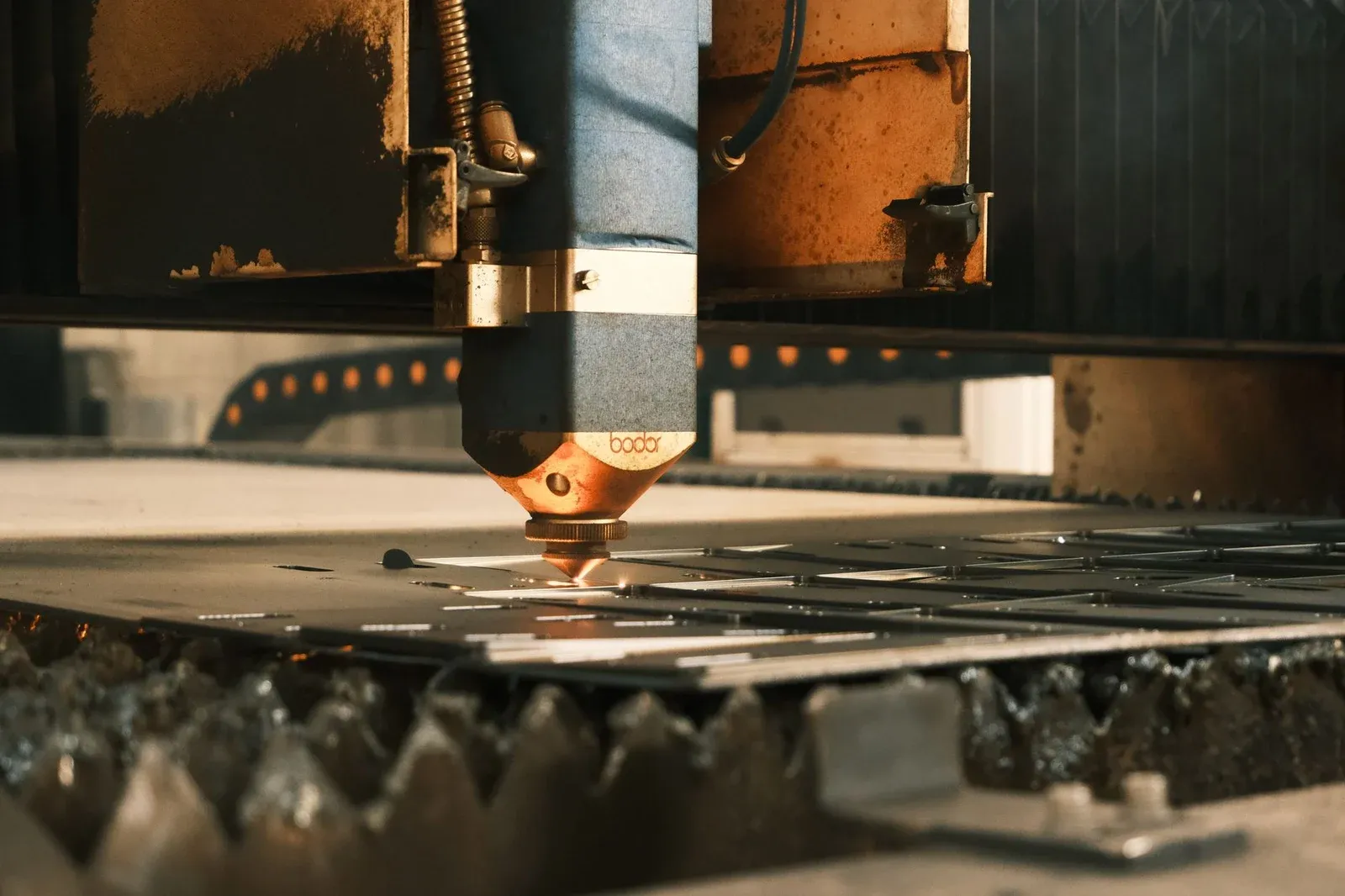Industrial cutting head positioned above a metal sheet on a slatted bed