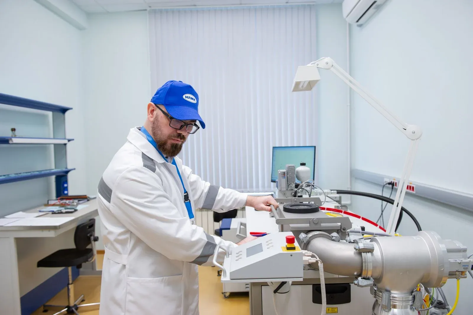 Laboratory technician operating analytical equipment beside a large sample chamber