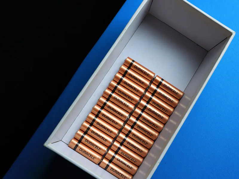 Top view of neatly arranged batteries in a box on a contrasting blue surface