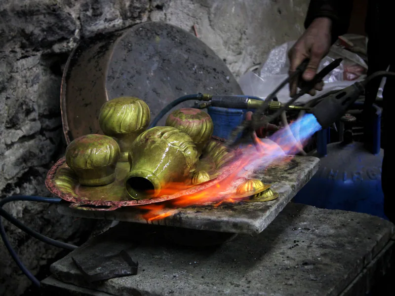 Craftsman heats ornate metalwork using blowtorch in Istanbul workshop