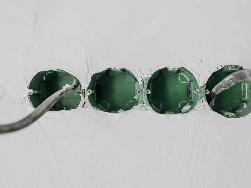 Close-up of green electrical boxes and wiring in a wall setup
