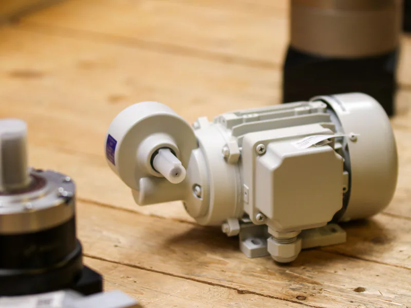 Close-up of a white industrial motor placed on a wooden surface inside a workshop