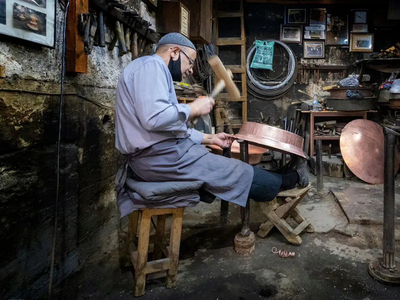 A skilled artisan working on copperware in a traditional workshop in Şanlıurfa, Türkiye