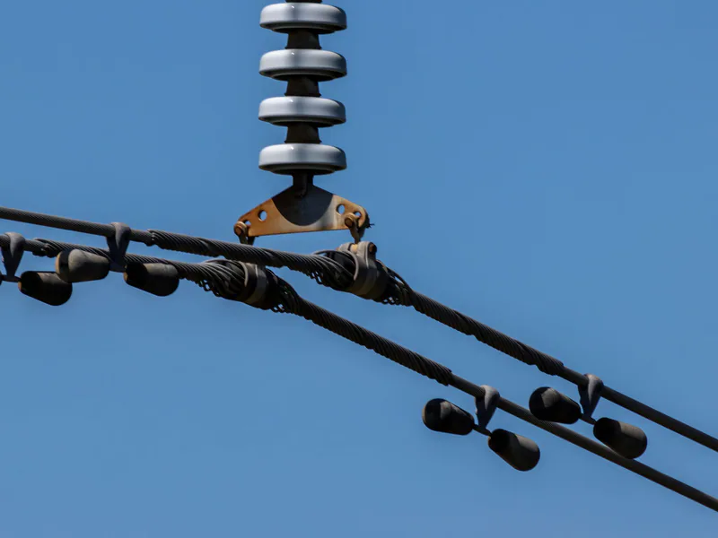 Detailed view of overhead power lines with blue sky background. Ideal for energy themes