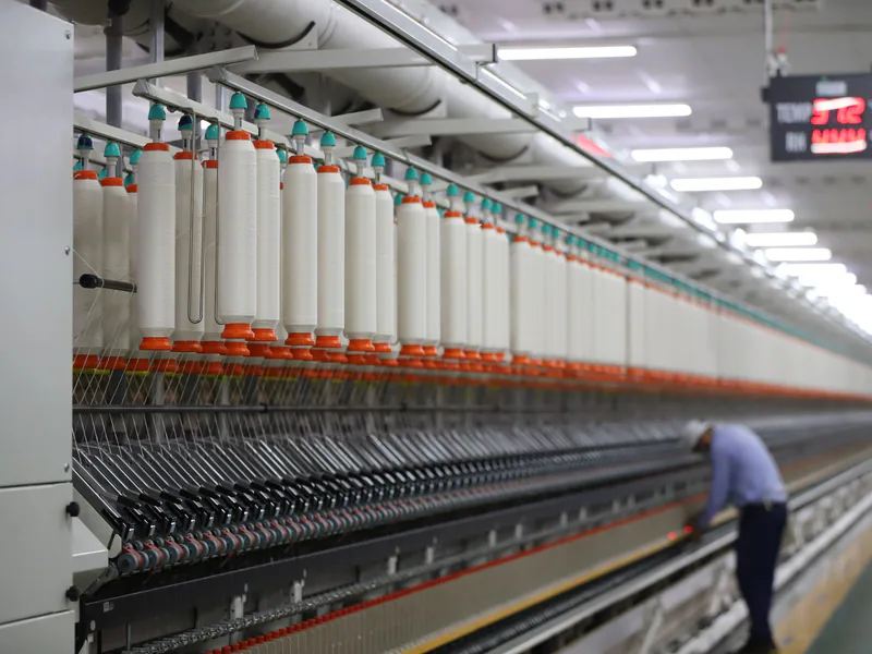 A textile factory in India showcasing modern spinning machinery with a worker