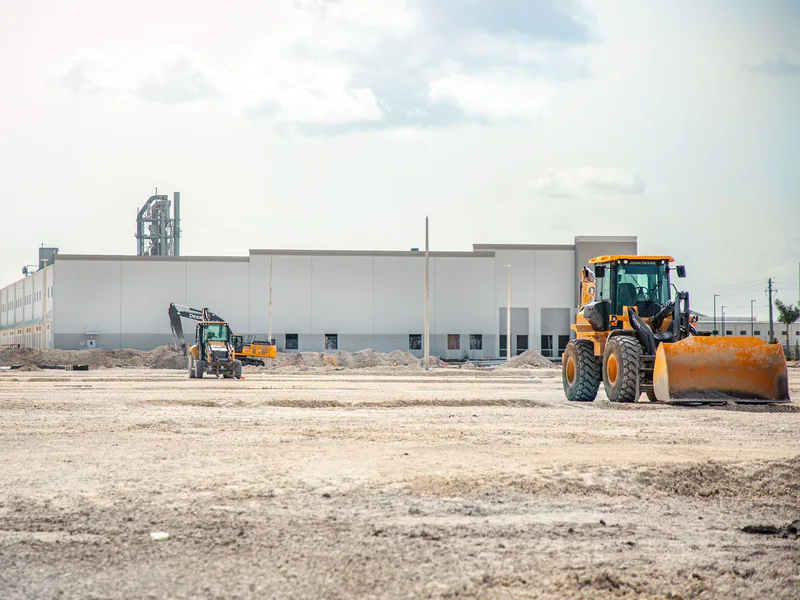 A large construction site featuring heavy machinery and industrial building in progress