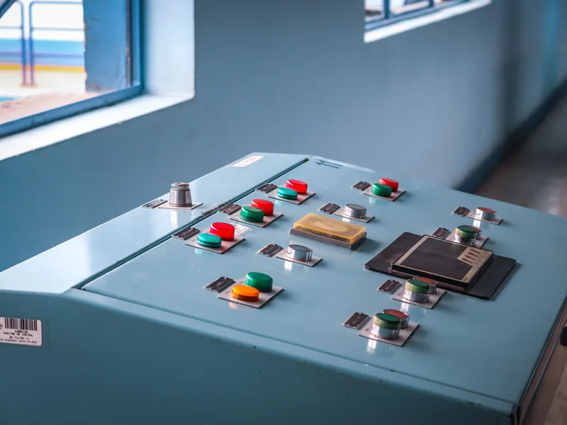 Close-up of an industrial control panel with colorful buttons in a factory setting