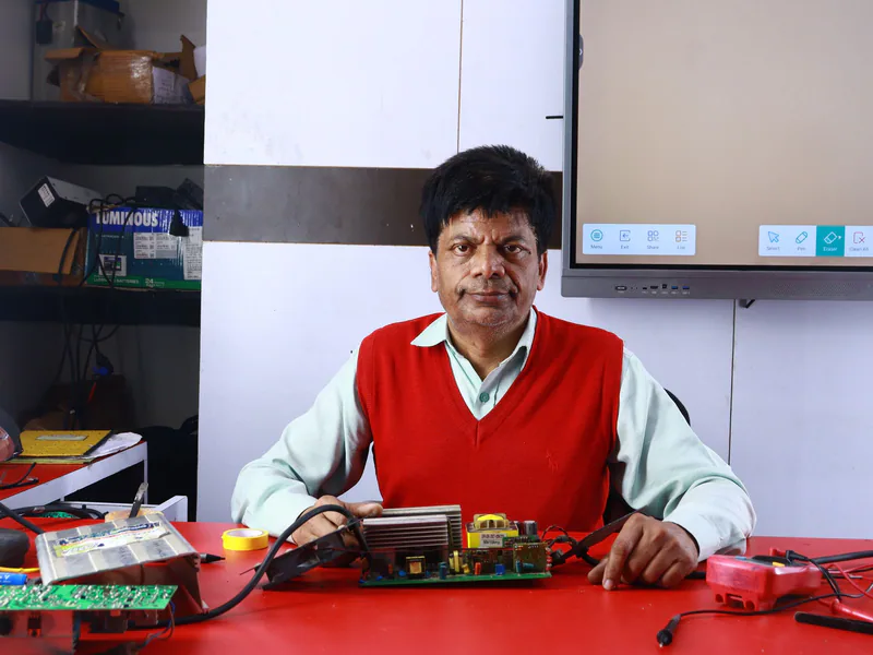 Adult male teaching electronics repair at a training institute, surrounded by circuits