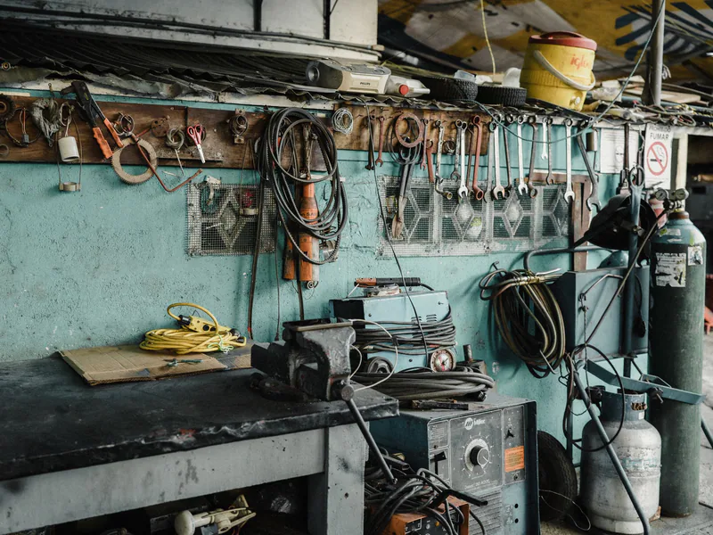 A cluttered workshop space with tools, machinery, and a vise, creating an industrial vibe