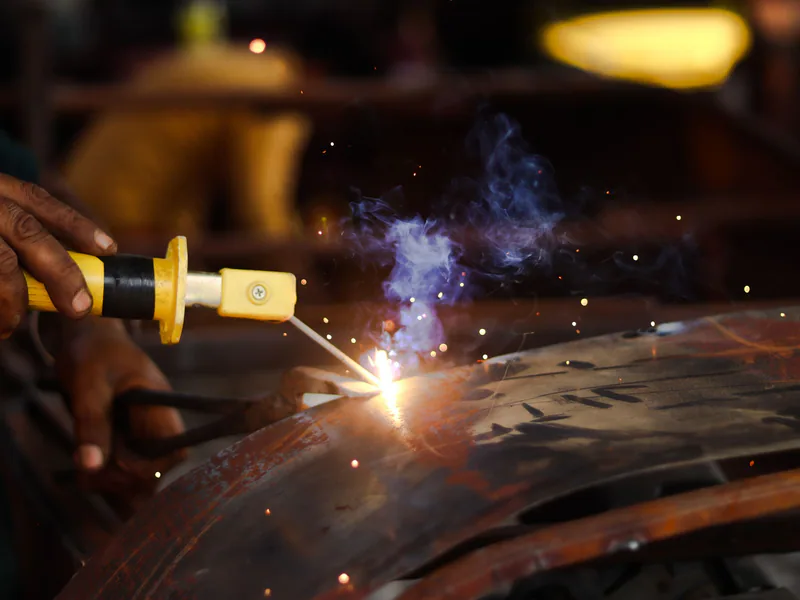 Close-up of a welder in action, creating sparks while working on metal indoors