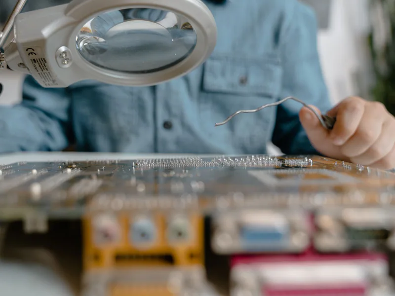 A detailed view of electronic circuit inspection using a magnifying glass and tools