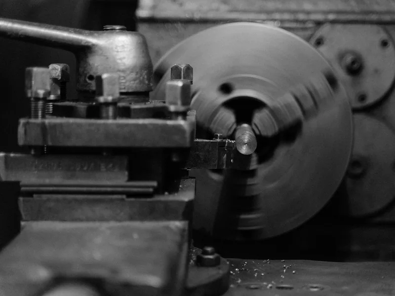Black and white close-up of an industrial lathe machine showing its intricate mechanical details