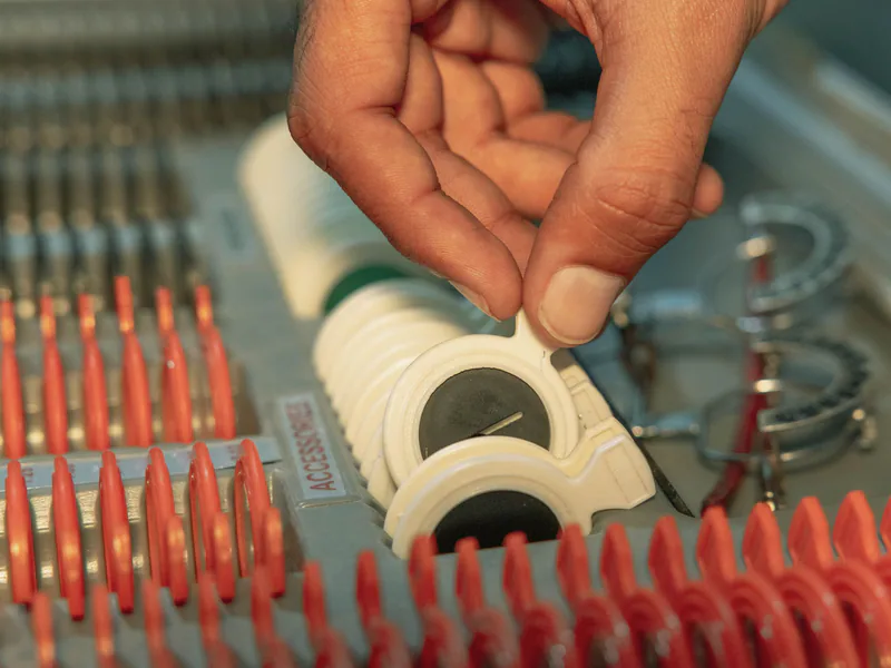 Detailed view of optometrist’s hand choosing lens from optical kit, highlighting precision in eye care