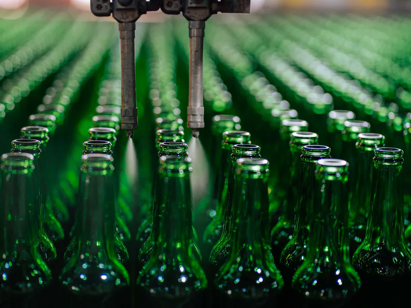 Rows of green glass bottles on an automated production line in a factory setting