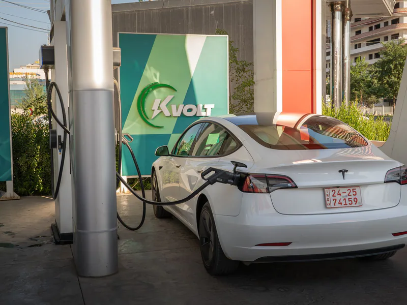 A white Tesla Model 3 charging at an outdoor electric vehicle station with Kvolt branding