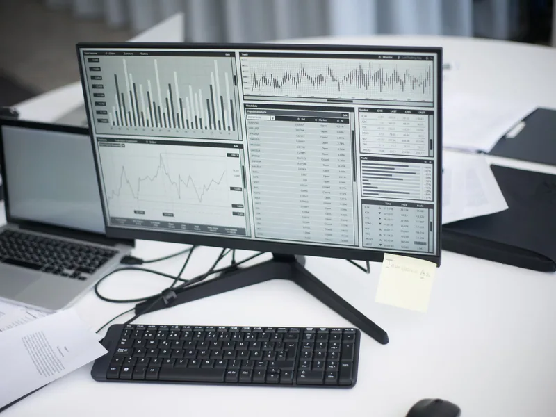 A professional workspace featuring computers and analytical graphs on a monitor, symbolizing modern business environment