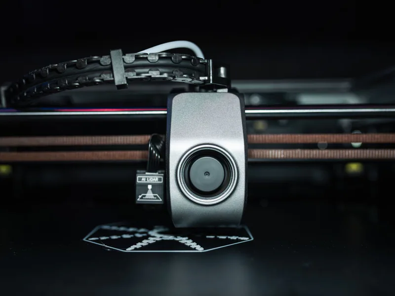 Detailed close-up of a 3D printer extrusion head in focus, showcasing modern technology