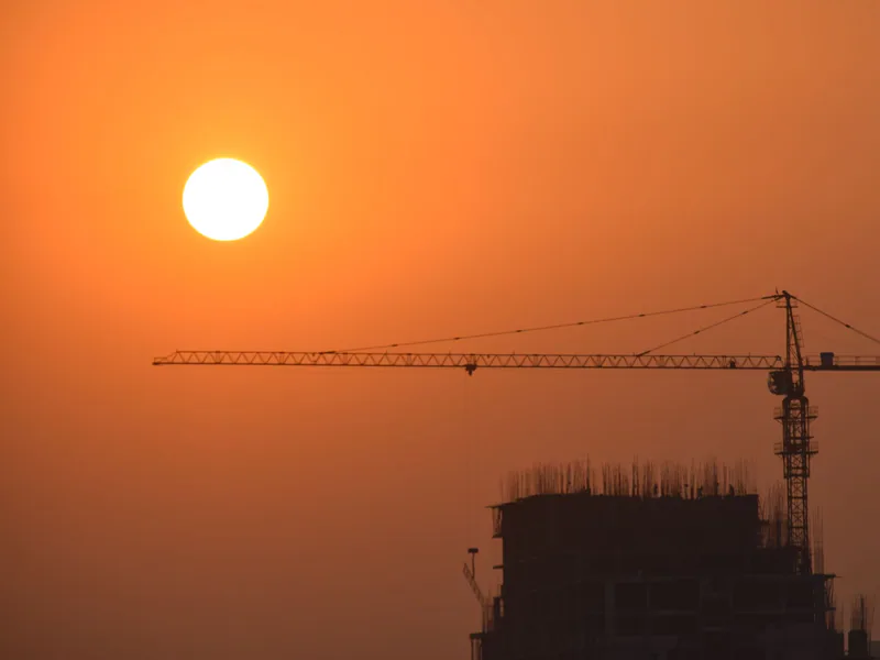 A striking silhouette of a construction crane set against a vibrant sunset sky in Faridabad, India