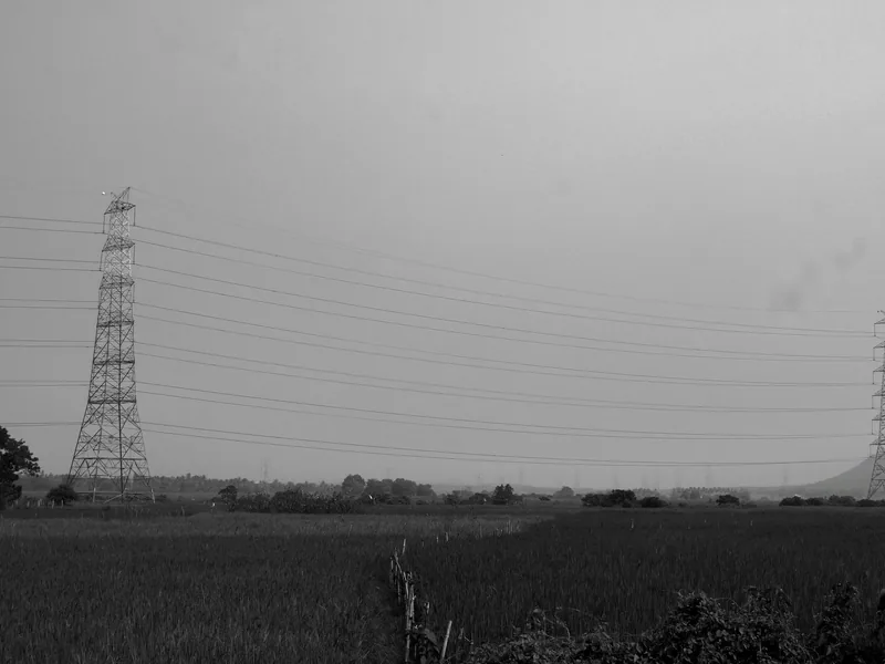 Black and white photo of transmission towers in the rural fields of Odisha, India