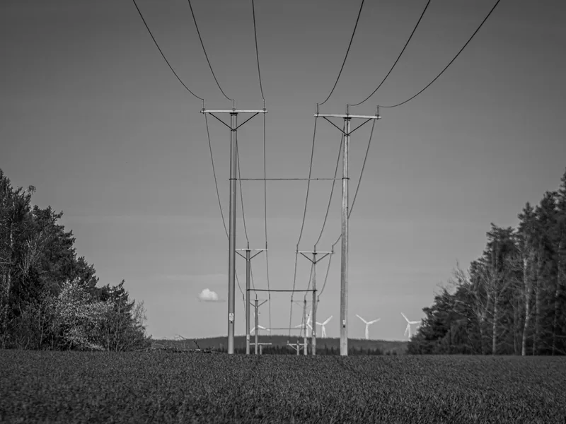 Monochrome view of power lines and distant wind turbines in Jönköping, Sweden
