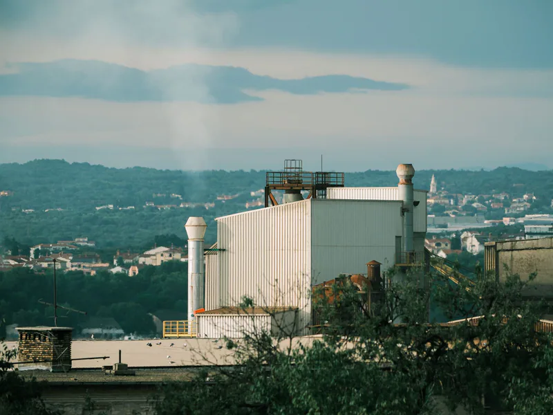 A factory building set against the scenic background of Hırvatistan’s verdant landscape