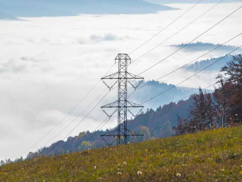 High voltage power tower in a foggy mountain landscape creating a dramatic scene