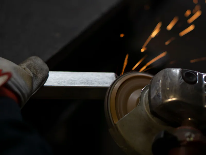 Angle grinder working on steel, emitting bright sparks. Industrial close-up shot