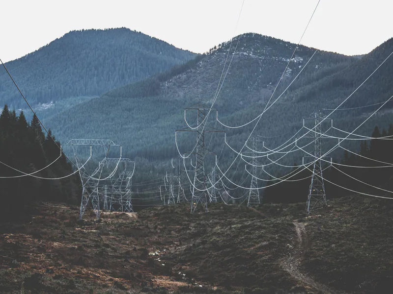 Power lines stretch across a rugged mountain landscape, showcasing infrastructure in nature