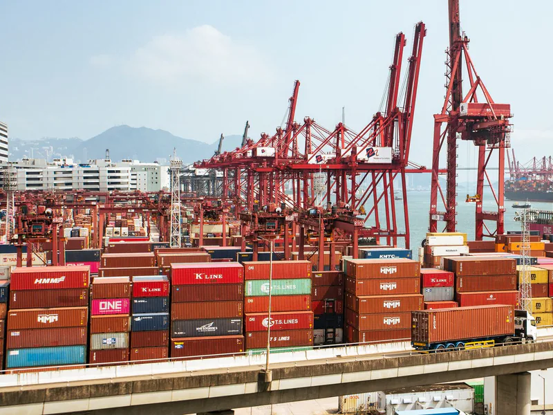 A bustling scene of cargo containers and cranes at a Hong Kong port, showcasing global trade