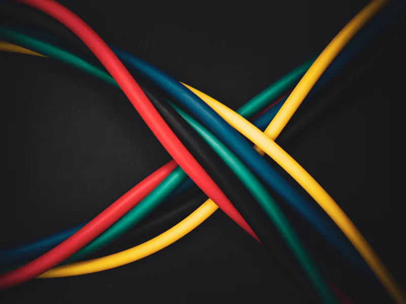Multi-colored cables intertwined against a dark background, showing technology connections