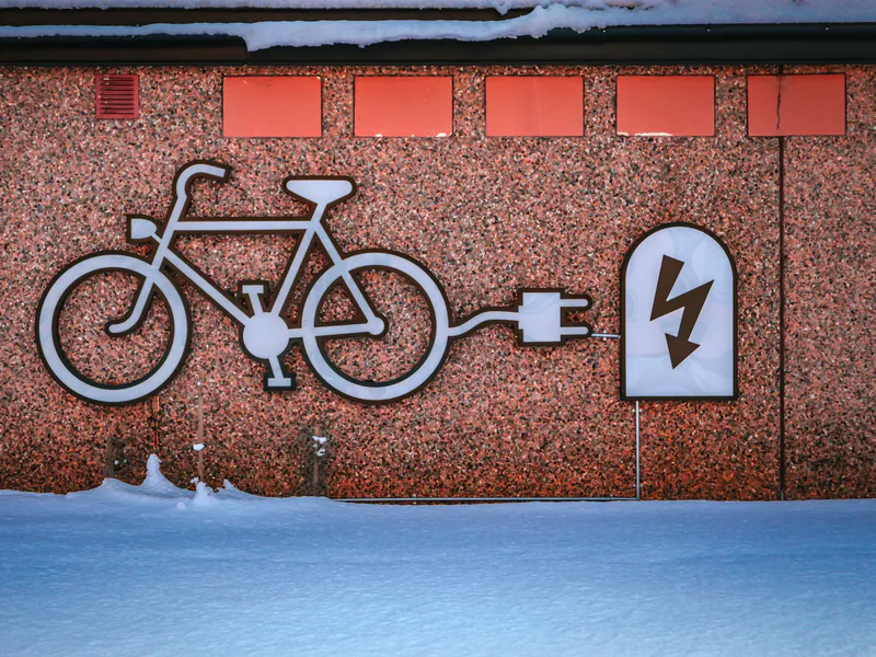 Electric bike charging graphic on a snowy urban wall, promoting renewable energy
