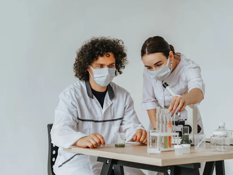 Two scientists working on experiments in a laboratory with microscopes and test tubes