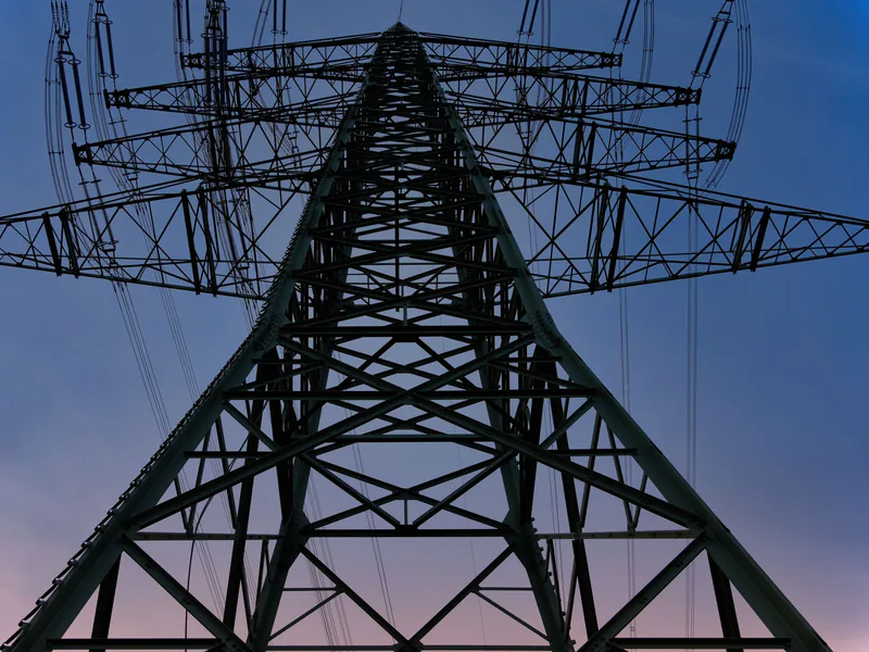 Low angle shot of a power transmission tower against a twilight sky, emphasizing industrial design