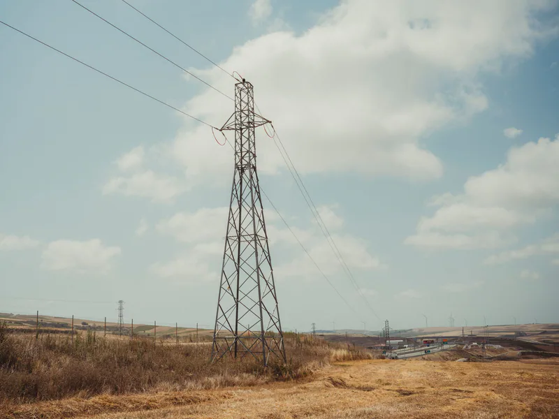 High voltage pylon in a countryside landscape under a blue sky with clouds