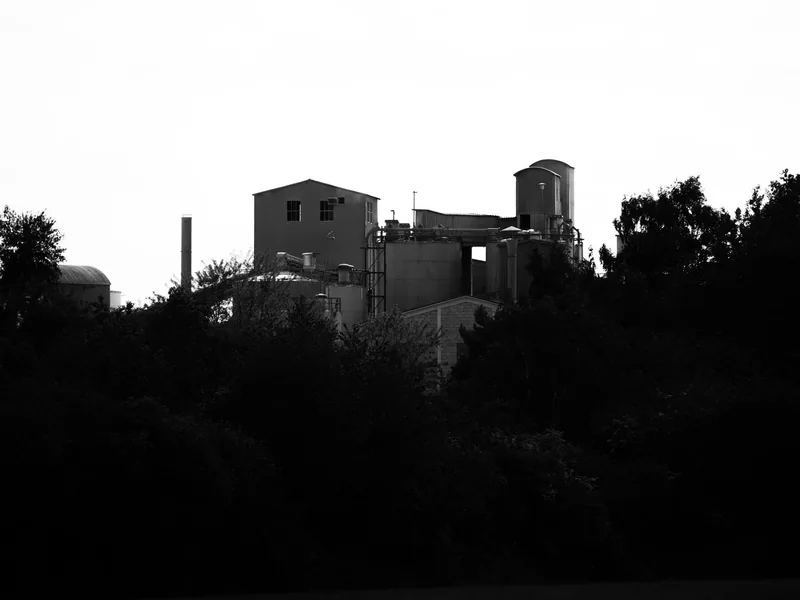 Black and white image of an industrial factory surrounded by trees in Andernach, Germany
