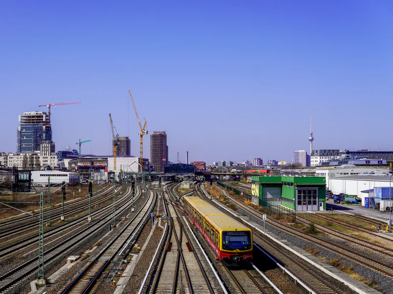A vibrant Berlin train scene featuring the iconic TV Tower and busy railroads